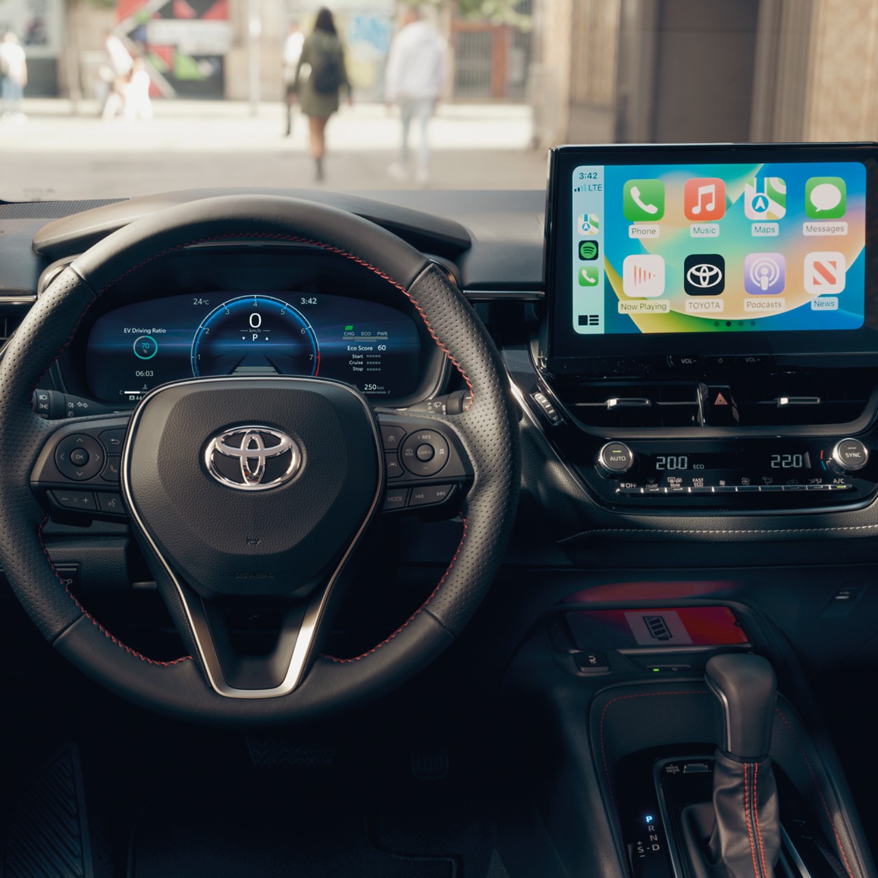 Dans un véhicule Toyota, un écran tactile multimédia intégré à un tableau de bord noir affiche l’écran d’accueil Apple CarPlay