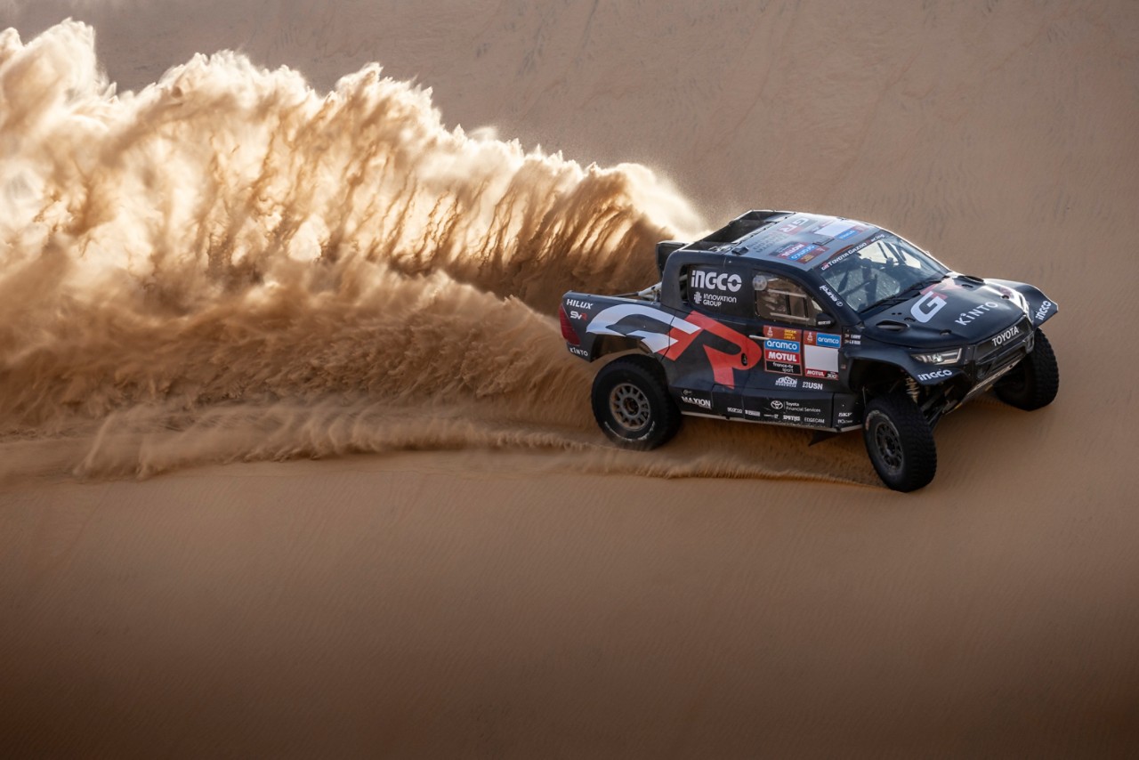 Hilux driving through desert kicking up sand